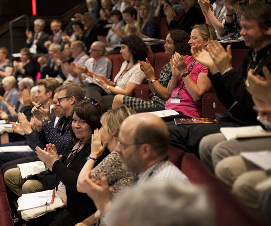 Attendees at Theatres Trust conference, sat in theatre auditorium, clapping.