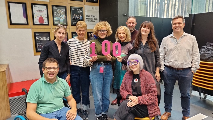 Group of people holding the number 100.