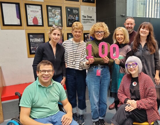 Group of people holding the number 100.